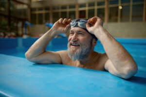 Healthy senior man swimming in indoor pool enjoying sportive lifestyle and active retirement