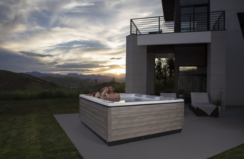 Couple in hot tub at sunset with mountain views and modern architecture, romantic evening setting