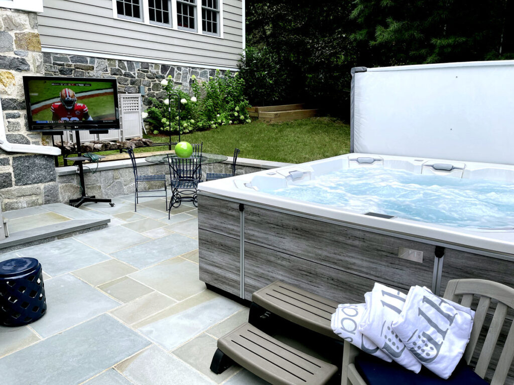 Hot tub installed on a backyard stone patio close to the back door