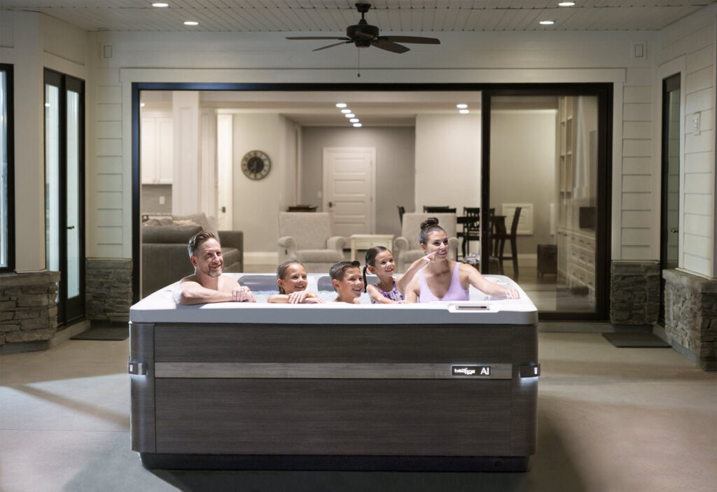 Modern hot tub on wooden deck with couple relaxing, white outdoor furniture visible, contemporary home setting