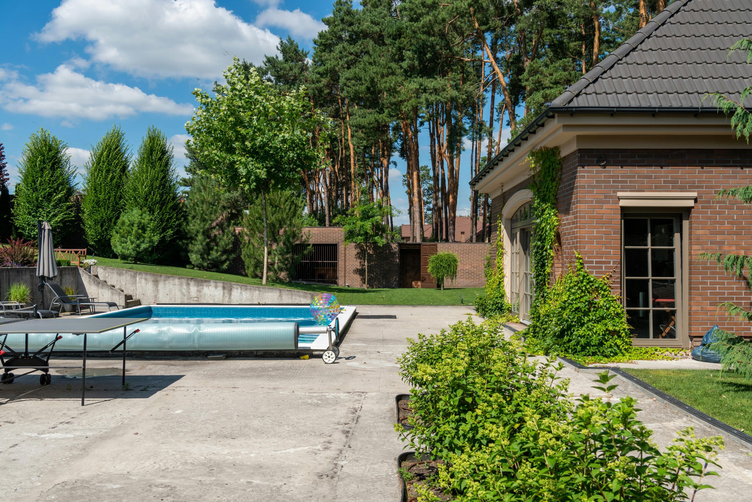 Covered inground swimming pool with winter cover and lounge chairs in residential backyard ready for winter season