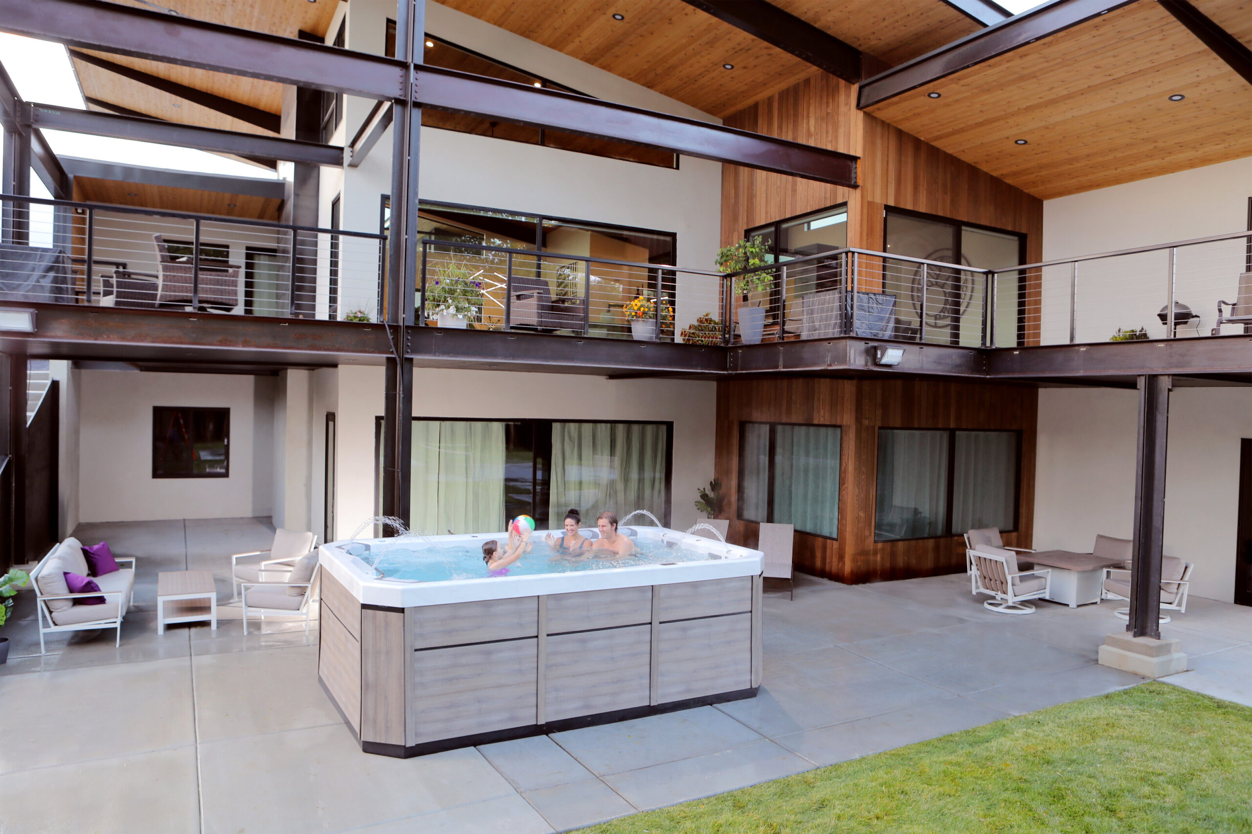 Family with children enjoying hot tub in modern architectural courtyard with contemporary home design