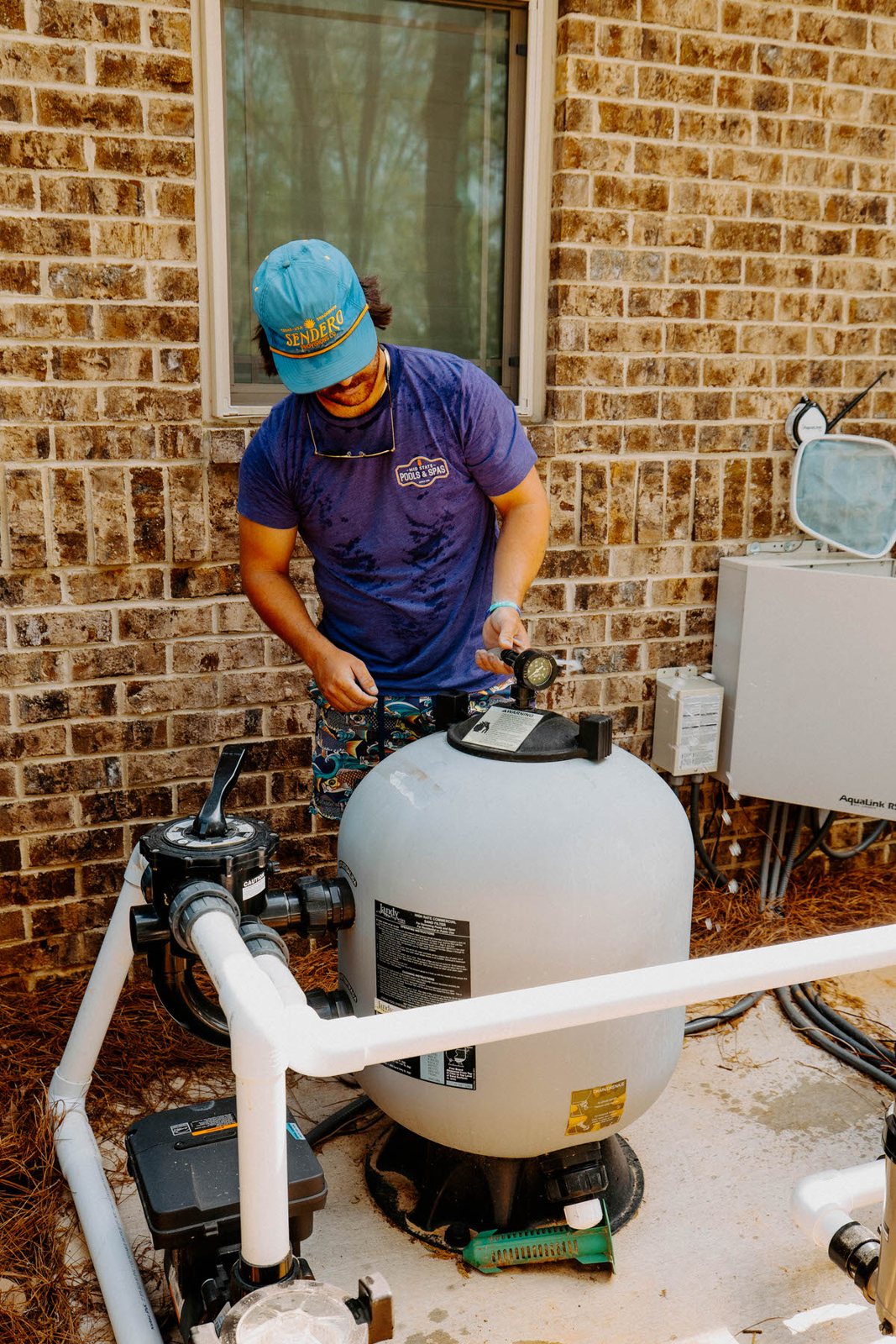 Pool technician inspecting a sand filter and pump for leaks in Middle Georgia