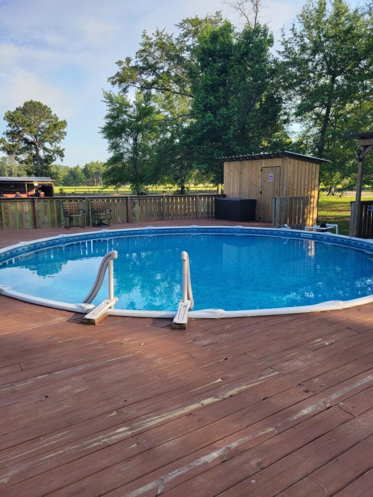 Round above ground pool on wooden deck surrounded by privacy fence in residential backyard